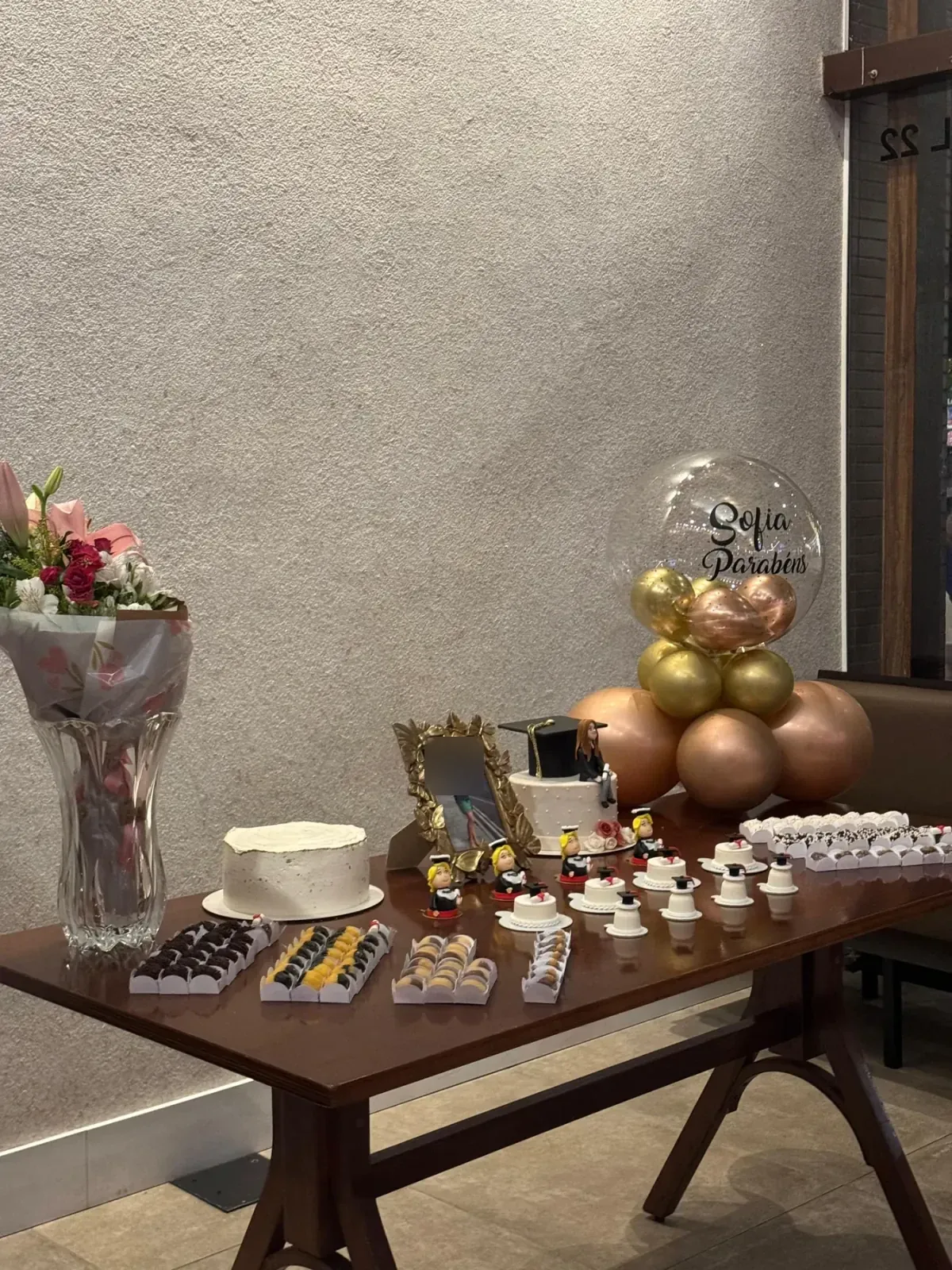 Mesa decorada com bolo, doces, flores e balões para uma celebração no restaurante